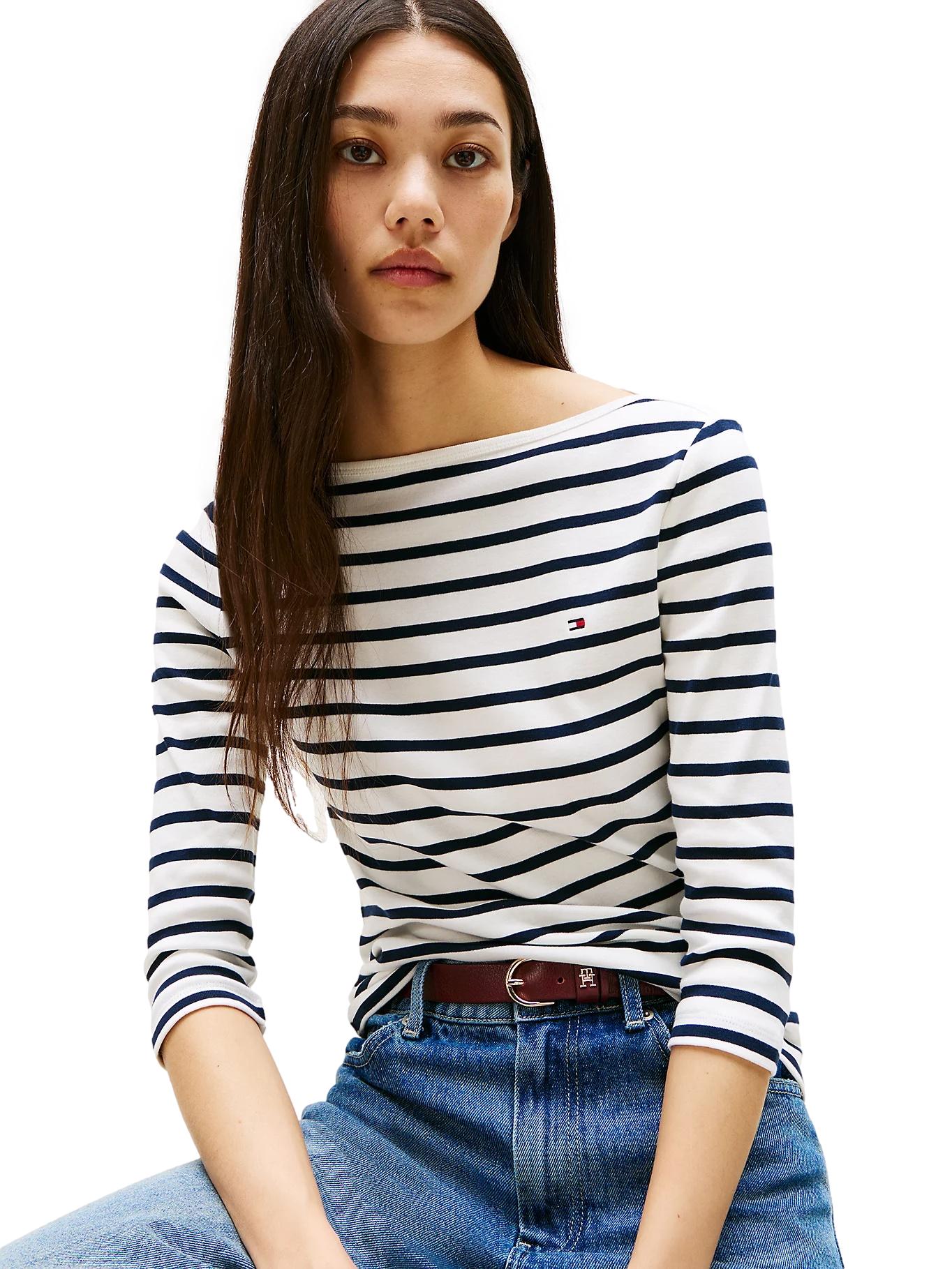 Hvit Tommy Hilfiger genser med båtnakk og smal passform, vist på modell i et stilfullt antrekk.